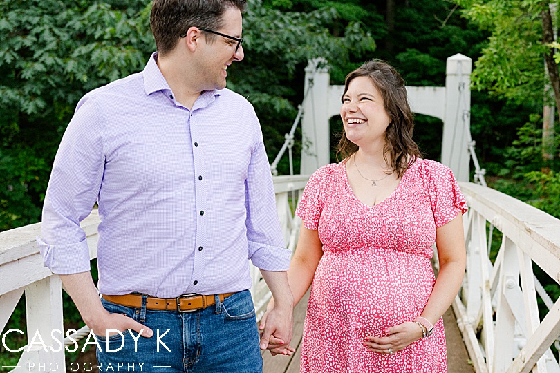 Husband and wife walking across bridge during Lenape Park Maternity. session