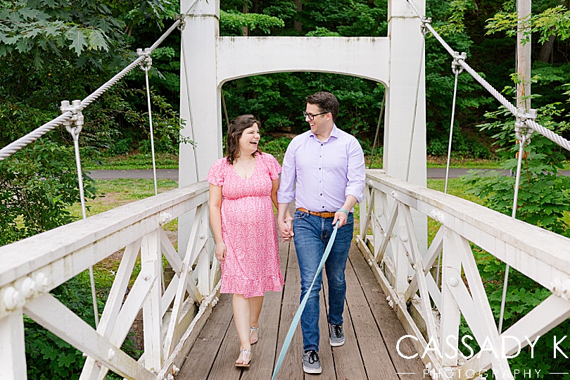 Man and woman walking across bridge at Lenape Park Maternity Session