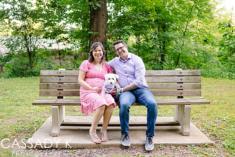 Man and pregnant woman sitting on bench during Lenape Park Maternity session