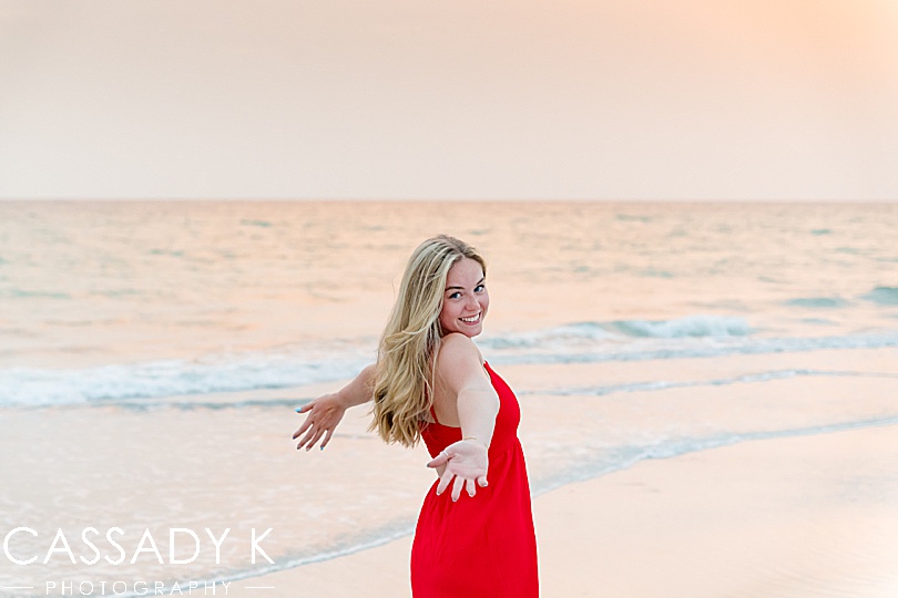 Girl in red dress posing on beach during sunset at Longboat Key Senior Portrait Session