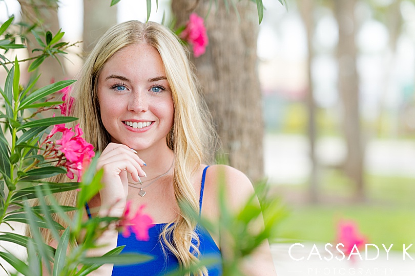 Girl in blue dress behind flowers during Longboat Key Senior Portrait Session