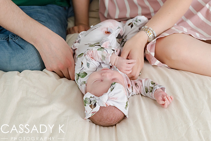 Mom and dad holding baby girl on bed during Lansdale Lifestyle Newborn Session