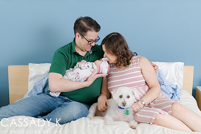 Mom and Dad sitting on bed with baby girl at Lansdale Lifestyle Newborn Session