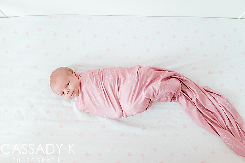 baby girl in pink swaddle on Disney sheets during Lansdale Lifestyle Newborn Session