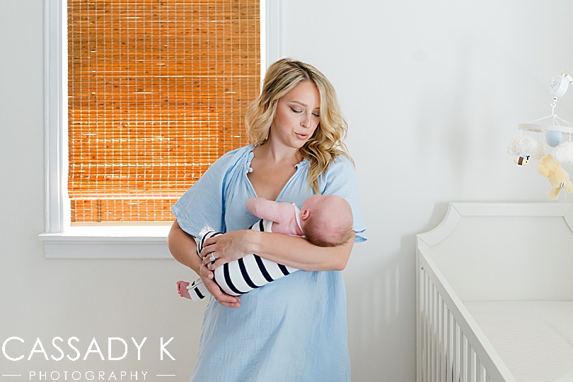 Mom quieting baby boy in his Classic Winnie the Pooh nursery during growing family lifestyle portraits 