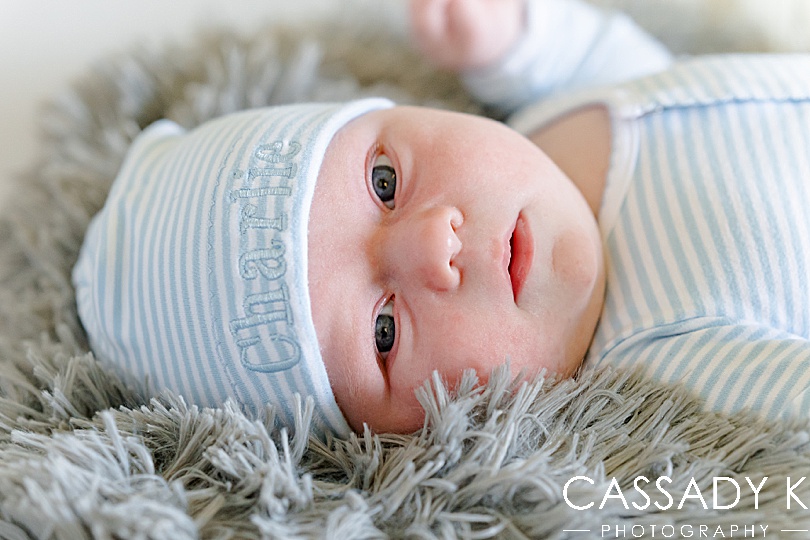 Closeup of baby's face while laying on a gray blanket during a growing family lifestyle session in Pittsburgh