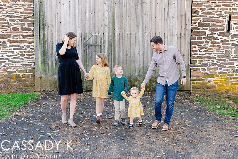 Family walks in front of a barn at a fall mini session