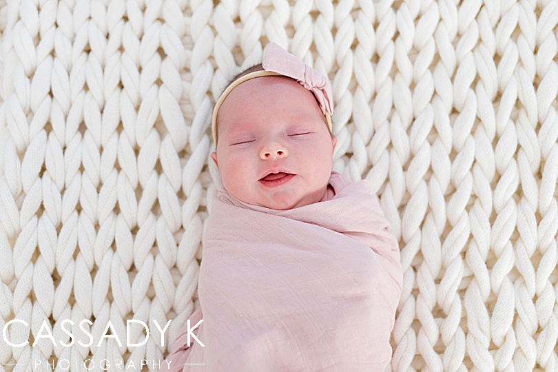 Baby girl lies peacefully on a large white knotted blanket during a Northern NJ newborn session