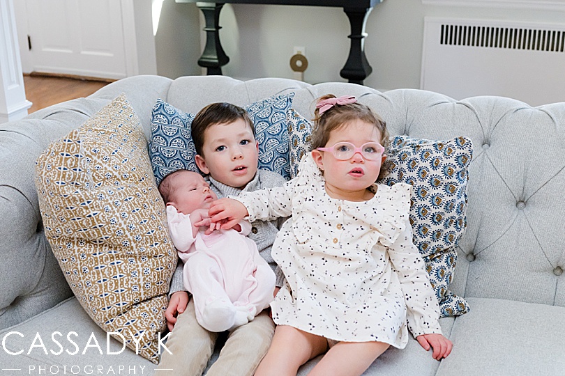 Older brother and sister holding baby sister during a northern NJ newborn session