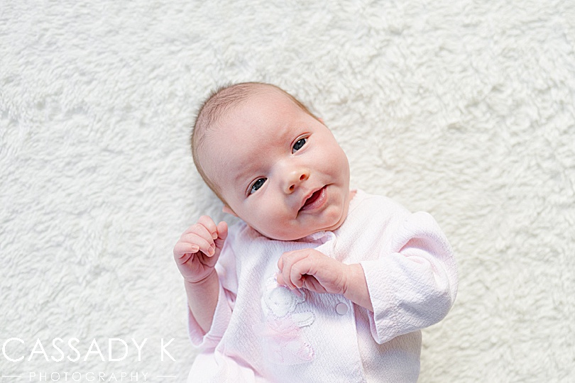 Newborn baby girl laying on a white fluffy blanket at a northern NJ photography session