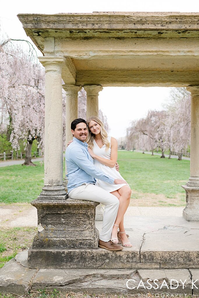 A couple sits on the stone gazebo in the middle of a row of Cherry Blossom trees in Fairmount Park, Philadelphia