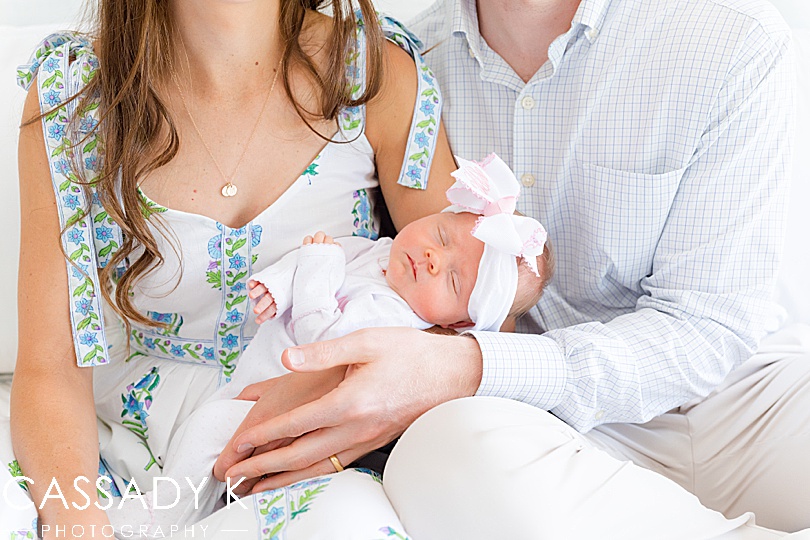 Newborn girl snuggles in both of her parents' arms during a family photo session in Doylestown, PA.
