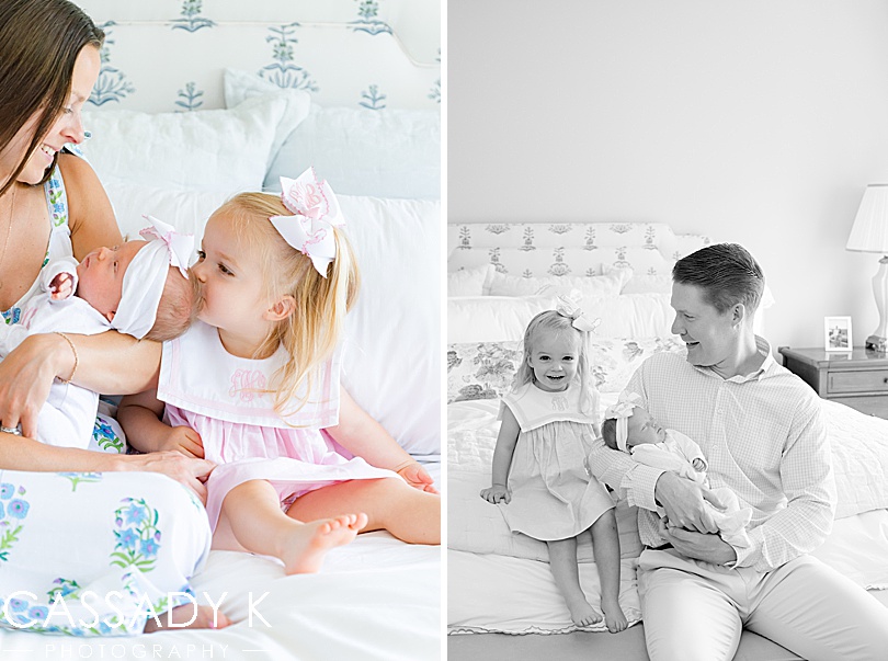 Toddler, big sister gives her newborn baby sister a kiss in their parents' dreamy blue bedroom outside of Philadelphia, PA